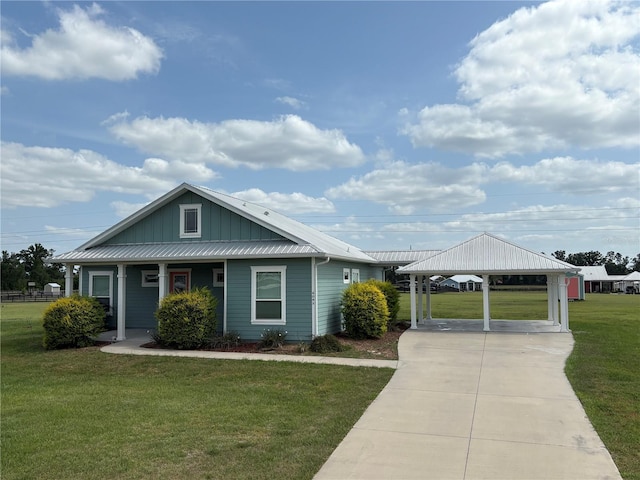 view of front facade with a front lawn, board and batten siding, a porch, driveway, and metal roof