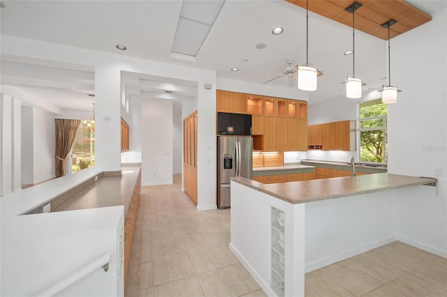 3200 NW 21st Ave, Gainesville, FL 32605 - kitchen featuring stainless steel refrigerator with ice dispenser, a ceiling fan, a peninsula, brown cabinetry, and decorative light fixtures
