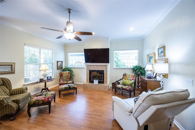 living room with recessed lighting, a tiled fireplace, a ceiling fan, ornamental molding, and wood finished floors