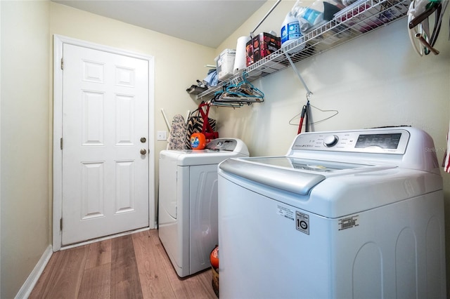 clothes washing area featuring baseboards, wood finished floors, laundry area, and washing machine and dryer