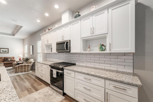 1272 NW 132nd Blvd, Newberry, FL 32669 - kitchen with stainless steel appliances, open shelves, light wood-style flooring, white cabinets, and decorative backsplash