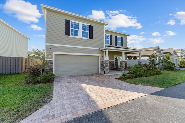 1487 NW 136th Blvd, Newberry, FL 32669 - view of front of house with driveway, stone siding, fence, a garage, and a porch