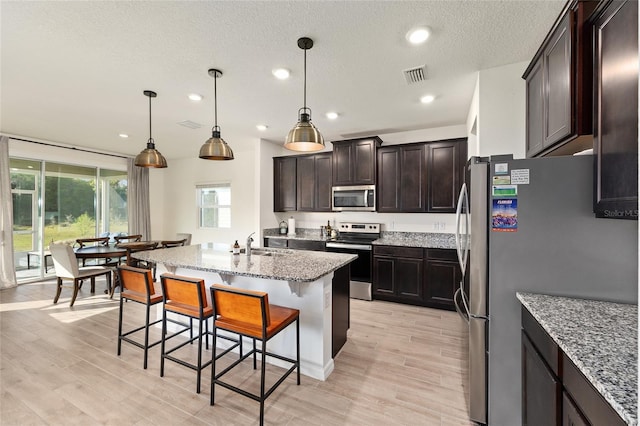 1487 NW 136th Blvd, Newberry, FL 32669 - kitchen with light stone counters, a sink, a breakfast bar, appliances with stainless steel finishes, and visible vents