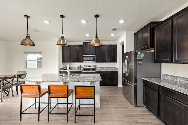 1487 NW 136th Blvd, Newberry, FL 32669 - kitchen featuring a breakfast bar area, light stone countertops, appliances with stainless steel finishes, hanging light fixtures, and visible vents