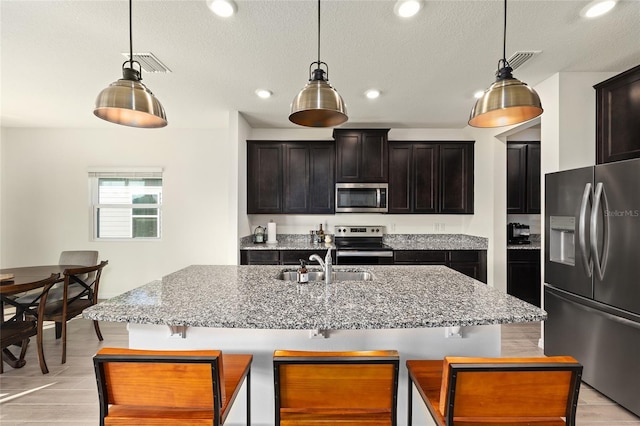 1487 NW 136th Blvd, Newberry, FL 32669 - kitchen featuring light stone counters, a sink, a breakfast bar area, appliances with stainless steel finishes, and visible vents