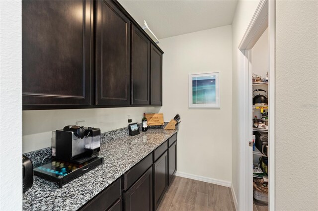 1487 NW 136th Blvd, Newberry, FL 32669 - kitchen featuring baseboards, stone countertops, dark brown cabinets, and light wood-type flooring