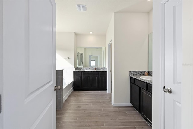1487 NW 136th Blvd, Newberry, FL 32669 - bathroom with wood finish floors, a sink, two vanities, and a bath