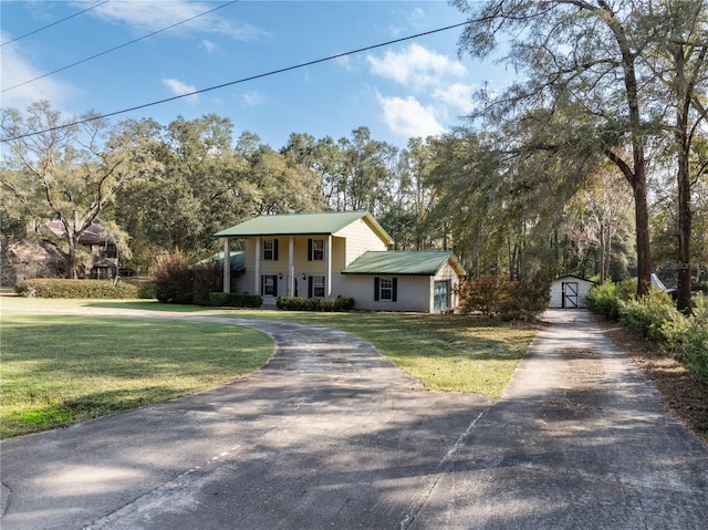 view of front of home with an outdoor structure, driveway, and a front lawn