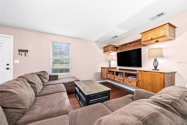 living area with dark wood-style flooring, visible vents, and a textured ceiling