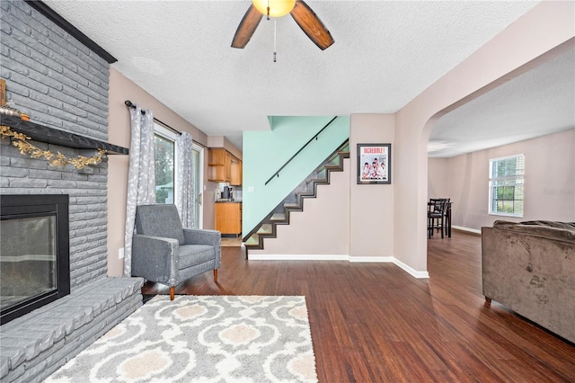 living room featuring baseboards, arched walkways, a ceiling fan, stairway, and wood finished floors