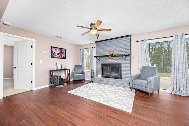 living area featuring visible vents, ceiling fan, wood finished floors, and a textured ceiling