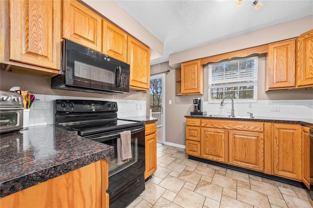 kitchen with baseboards, a textured ceiling, backsplash, black appliances, and a sink