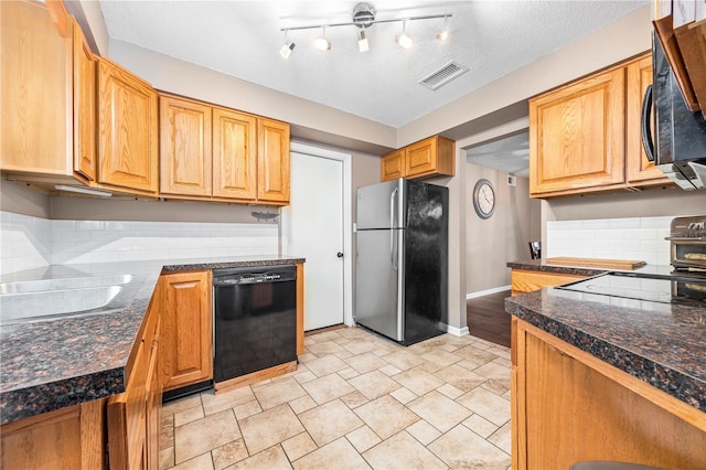 kitchen with visible vents, baseboards, black dishwasher, freestanding refrigerator, and range