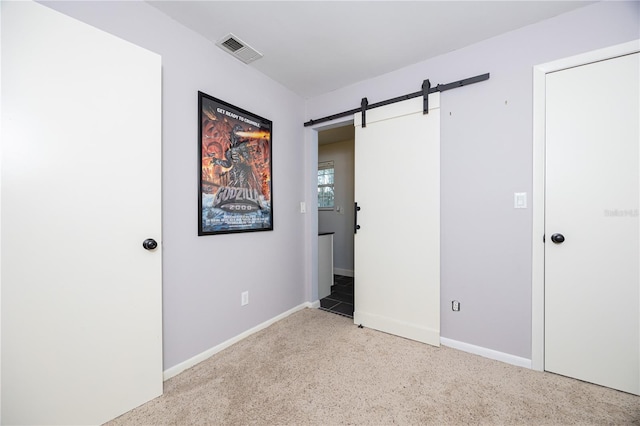 empty room with carpet floors, baseboards, visible vents, and a barn door