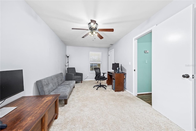carpeted office space featuring baseboards and a ceiling fan