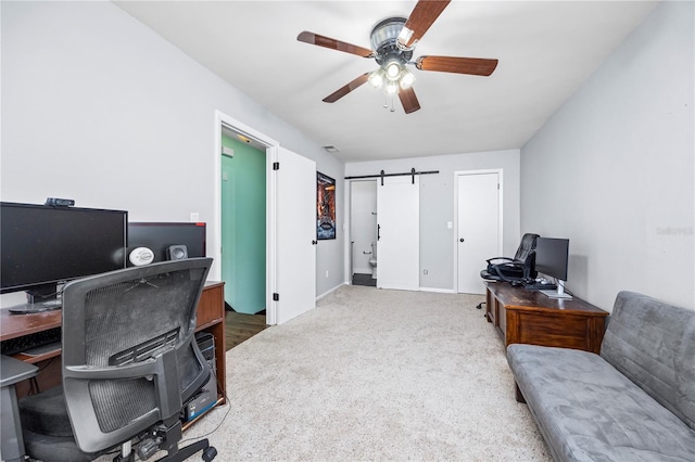 carpeted office featuring a ceiling fan and a barn door