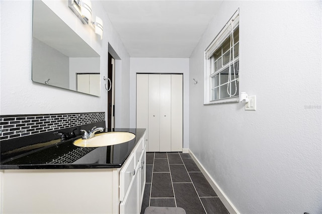 bathroom featuring tasteful backsplash, vanity, baseboards, and tile patterned floors