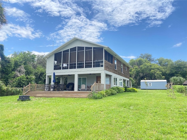 rear view of property featuring a lawn, a sunroom, and a deck