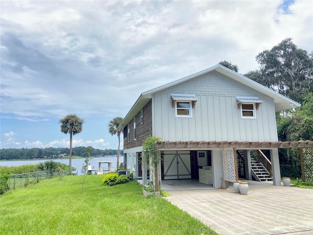 view of home's exterior with a water view, stairs, a garage, concrete driveway, and a yard