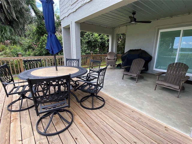 wooden terrace with a ceiling fan, area for grilling, and outdoor dining space