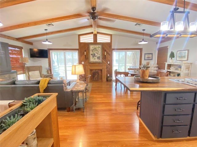 kitchen featuring open floor plan, vaulted ceiling with beams, light wood finished floors, and visible vents