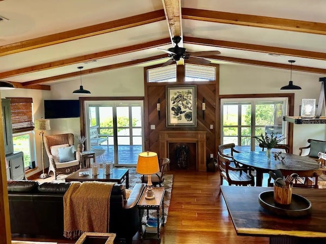 living area with ceiling fan, wood finished floors, vaulted ceiling with beams, and plenty of natural light
