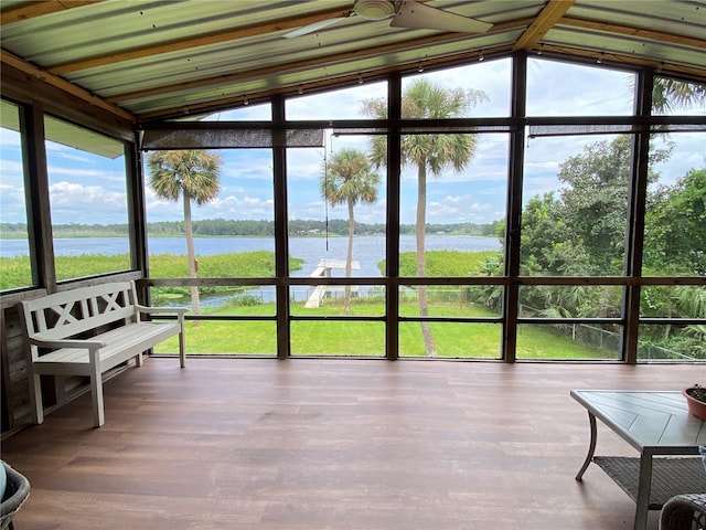 sunroom / solarium featuring a water view, a wall of windows, lofted ceiling, and wood finished floors