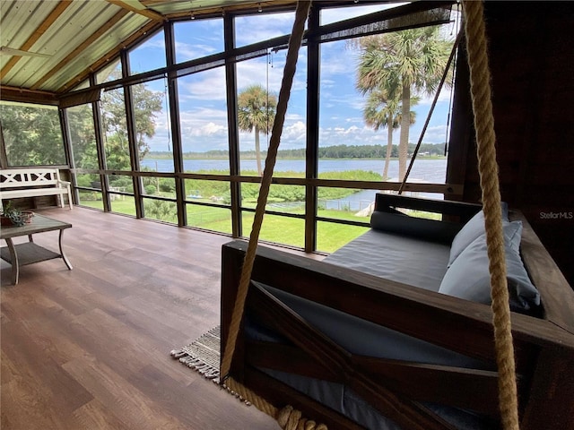 sunroom with expansive windows, a water view, lofted ceiling, and wood finished floors