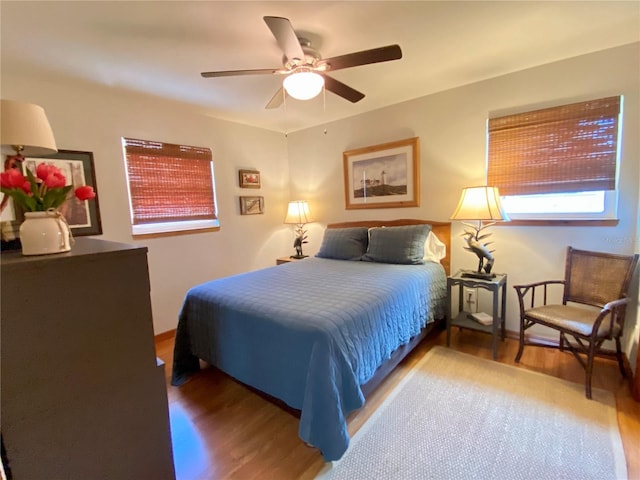 bedroom with a ceiling fan, baseboards, and wood finished floors