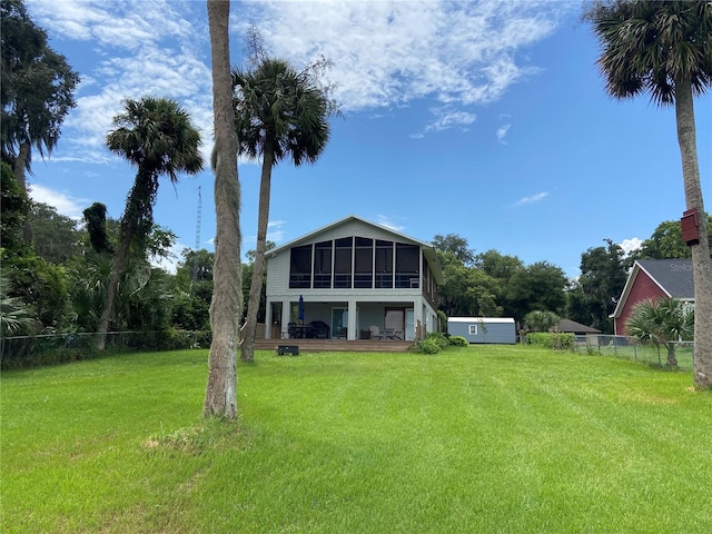 back of property featuring a sunroom, fence, and a yard