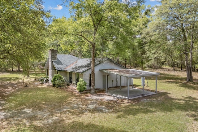 rear view of house with a chimney and a lawn