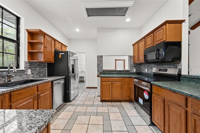 kitchen featuring light tile patterned flooring, a sink, brown cabinets, and appliances with stainless steel finishes