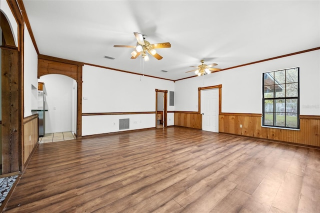 spare room featuring a wainscoted wall, visible vents, crown molding, wood finished floors, and a ceiling fan