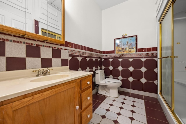 full bath with tile walls, a wainscoted wall, toilet, vanity, and a stall shower