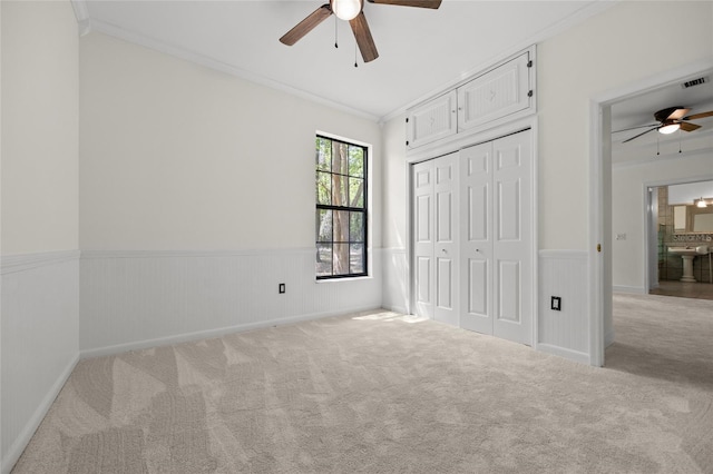 unfurnished bedroom with crown molding, carpet, and wainscoting