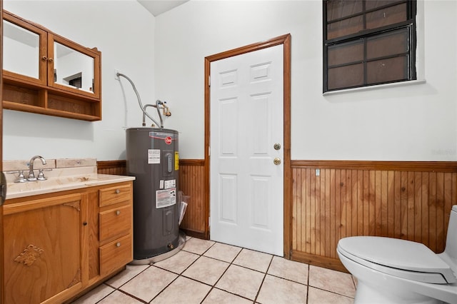 bathroom featuring toilet, wooden walls, wainscoting, tile patterned flooring, and electric water heater
