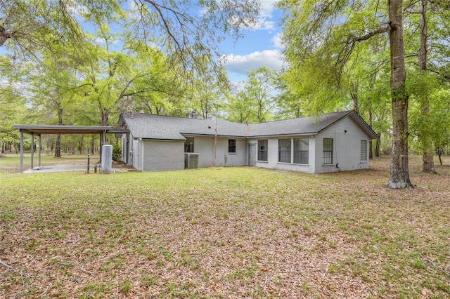 back of house with cooling unit, a detached carport, stucco siding, and a yard