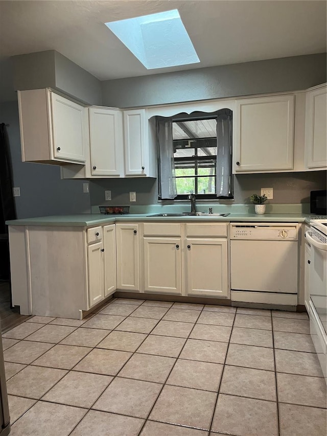 kitchen with light tile patterned flooring, white appliances, light countertops, a sink, and a skylight
