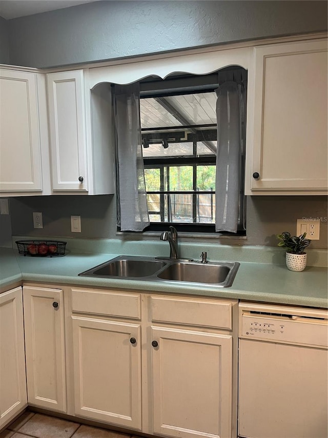 kitchen featuring light countertops, white dishwasher, white cabinetry, and a sink