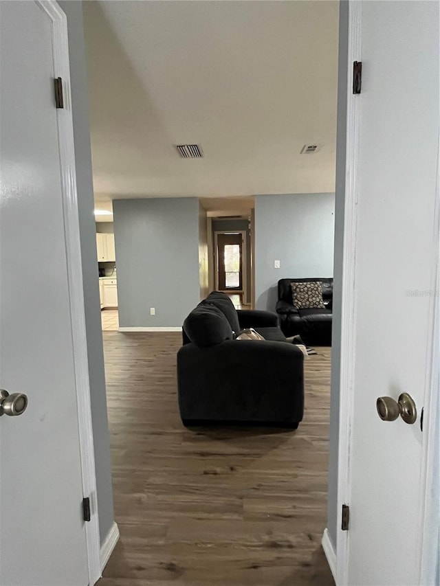 hallway featuring visible vents, baseboards, and dark wood-style floors