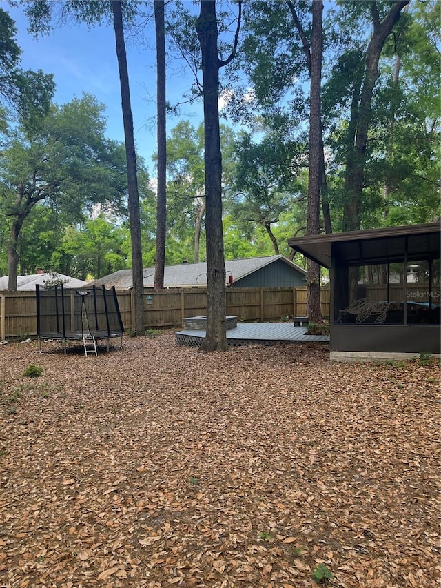 view of yard with a sunroom, a fenced backyard, and a trampoline
