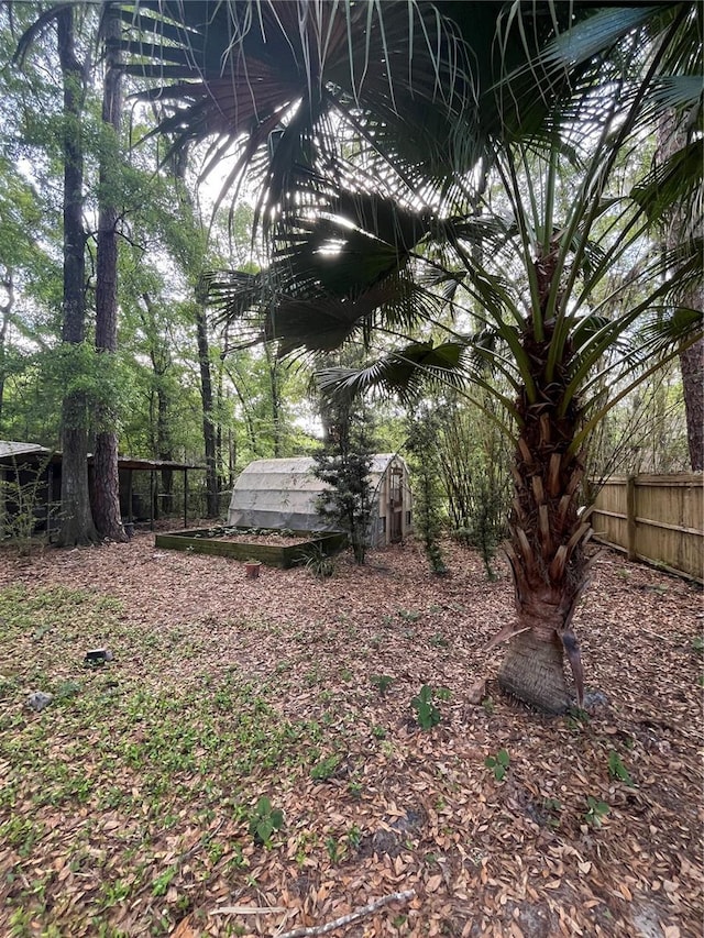 view of yard featuring fence, an outdoor structure, and a greenhouse