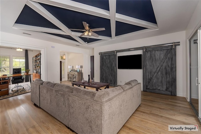living room with light wood-type flooring, a barn door, coffered ceiling, and a ceiling fan
