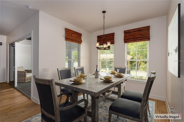 dining space with baseboards, a notable chandelier, and light wood-type flooring