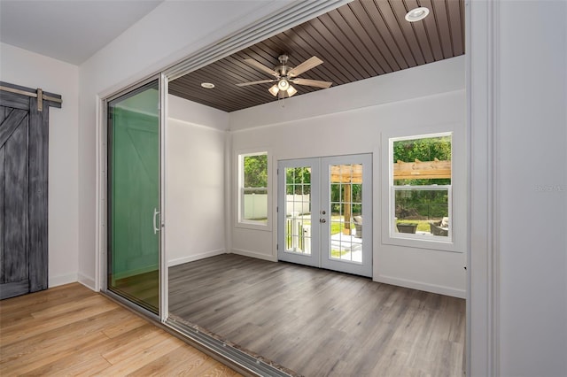 interior space with french doors, a barn door, light wood-style floors, and a healthy amount of sunlight