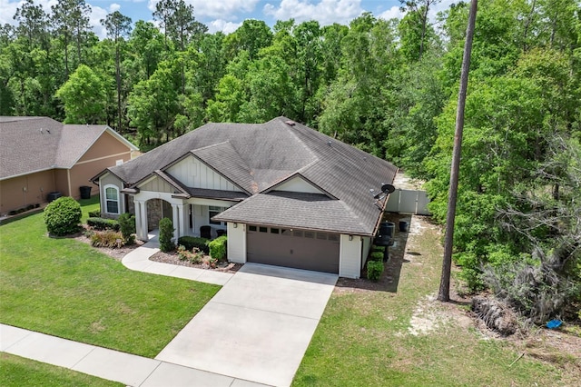 view of front of house featuring roof with shingles, a front lawn, a garage, board and batten siding, and concrete driveway