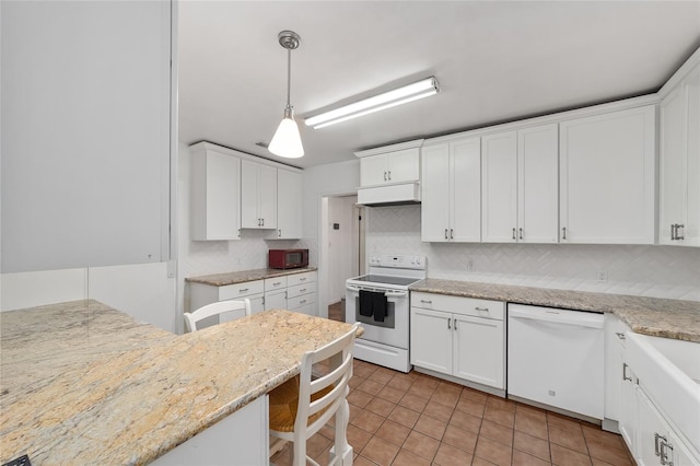 1711 NW 10th Ave, Gainesville, FL 32605 - kitchen with white appliances, decorative backsplash, white cabinets, and a kitchen breakfast bar