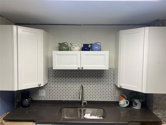 kitchen with tasteful backsplash, a sink, and white cabinetry