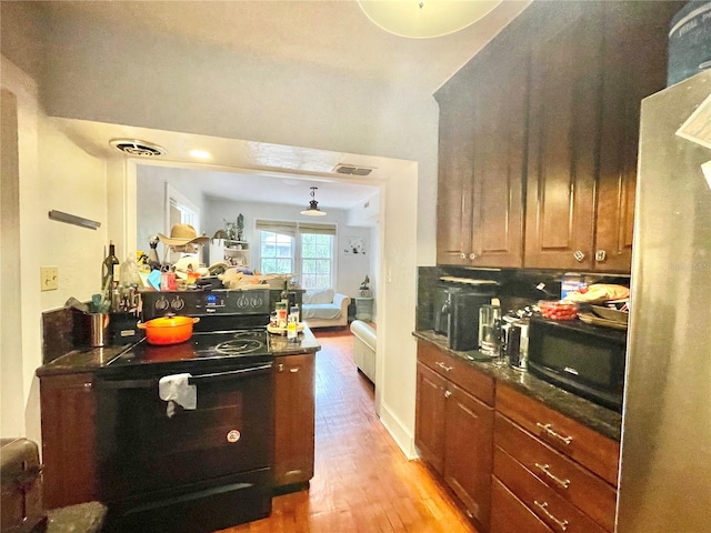 1035 NE 3rd Ave, Gainesville, FL 32601 - kitchen featuring black microwave, light wood-style flooring, freestanding refrigerator, and brown cabinetry