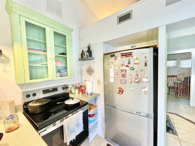 1035 NE 3rd Ave, Gainesville, FL 32601 - kitchen featuring freestanding refrigerator, stainless steel electric range oven, light tile patterned floors, light countertops, and glass insert cabinets